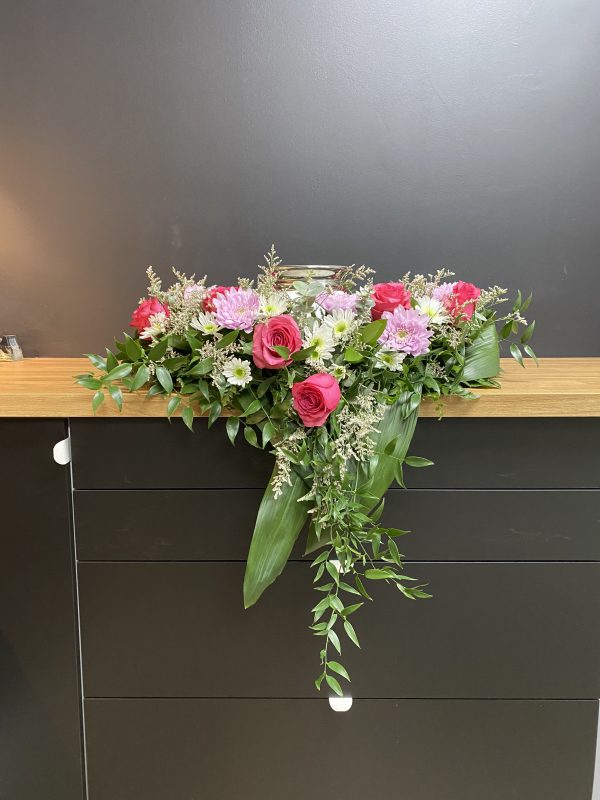 Composition florale funéraire avec urne, fleurs dans les tons doux et pastels, cascade de fleurs deuil, Fleuriste Foliole Rosemère.